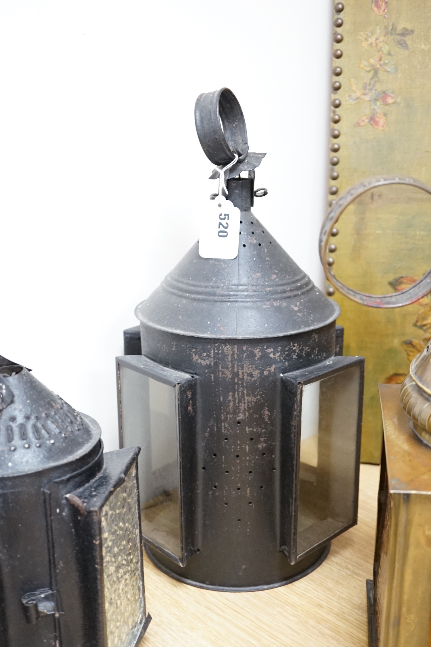 Three 19th century candle lanterns, one brass 45cm high, two black painted steel 45cm & 35cm high